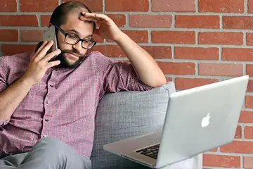 Frustrated man on the phone staring at a laptop